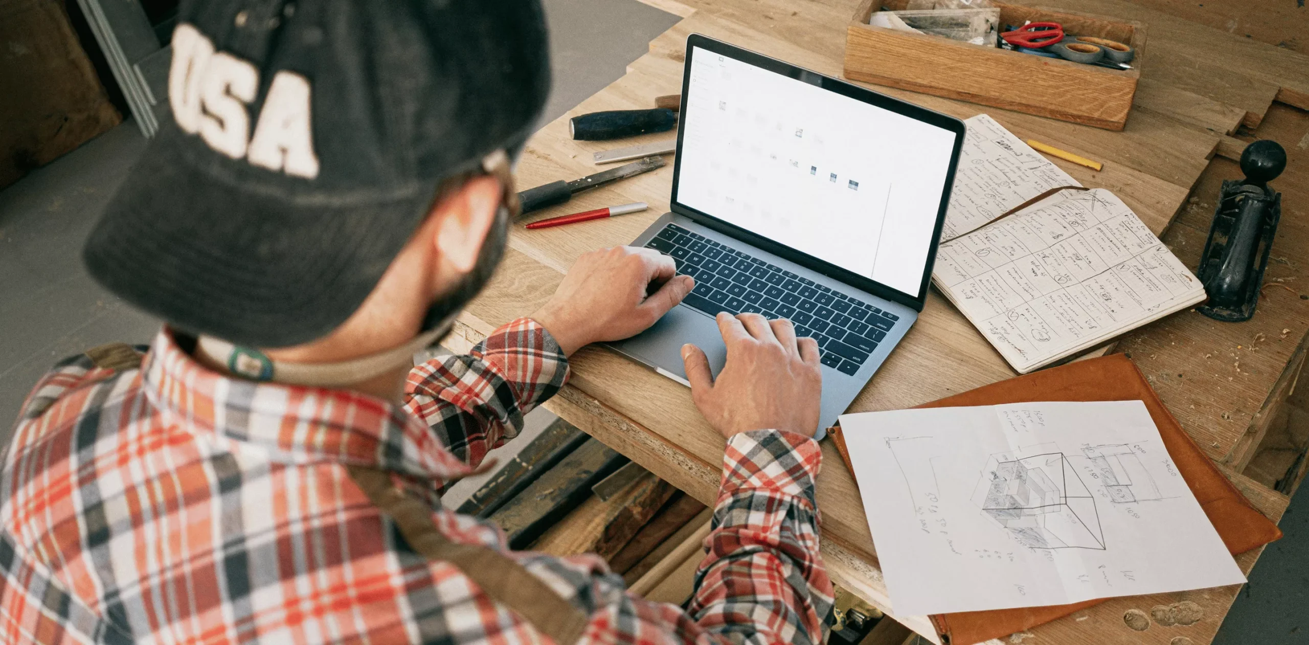 Worker using laptop with plans