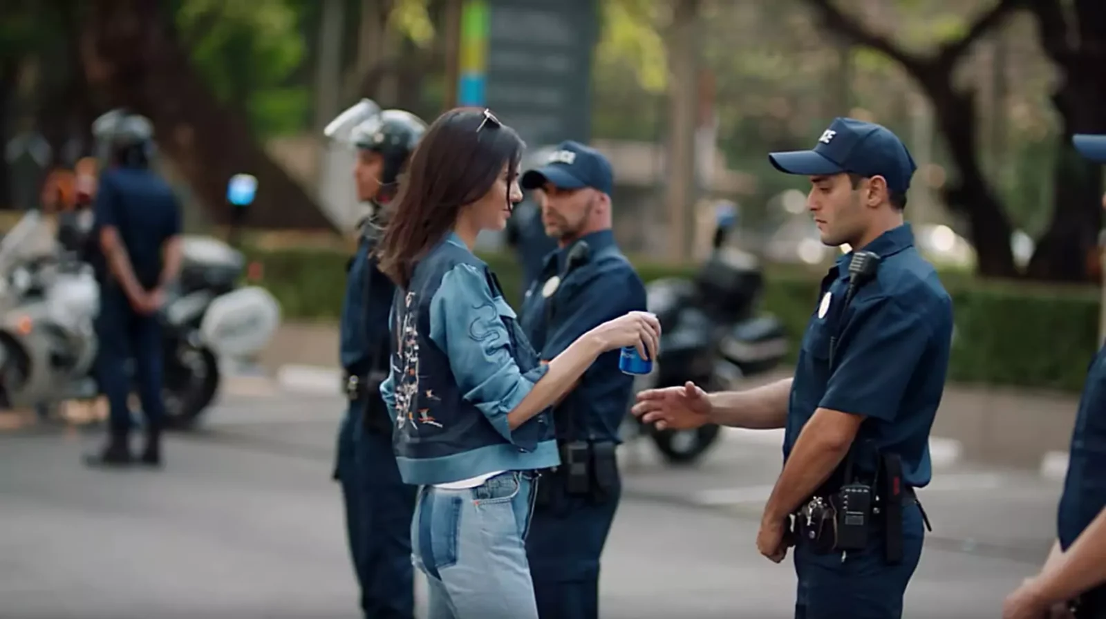 Kendall Jenner passes a police officer a Pepsi